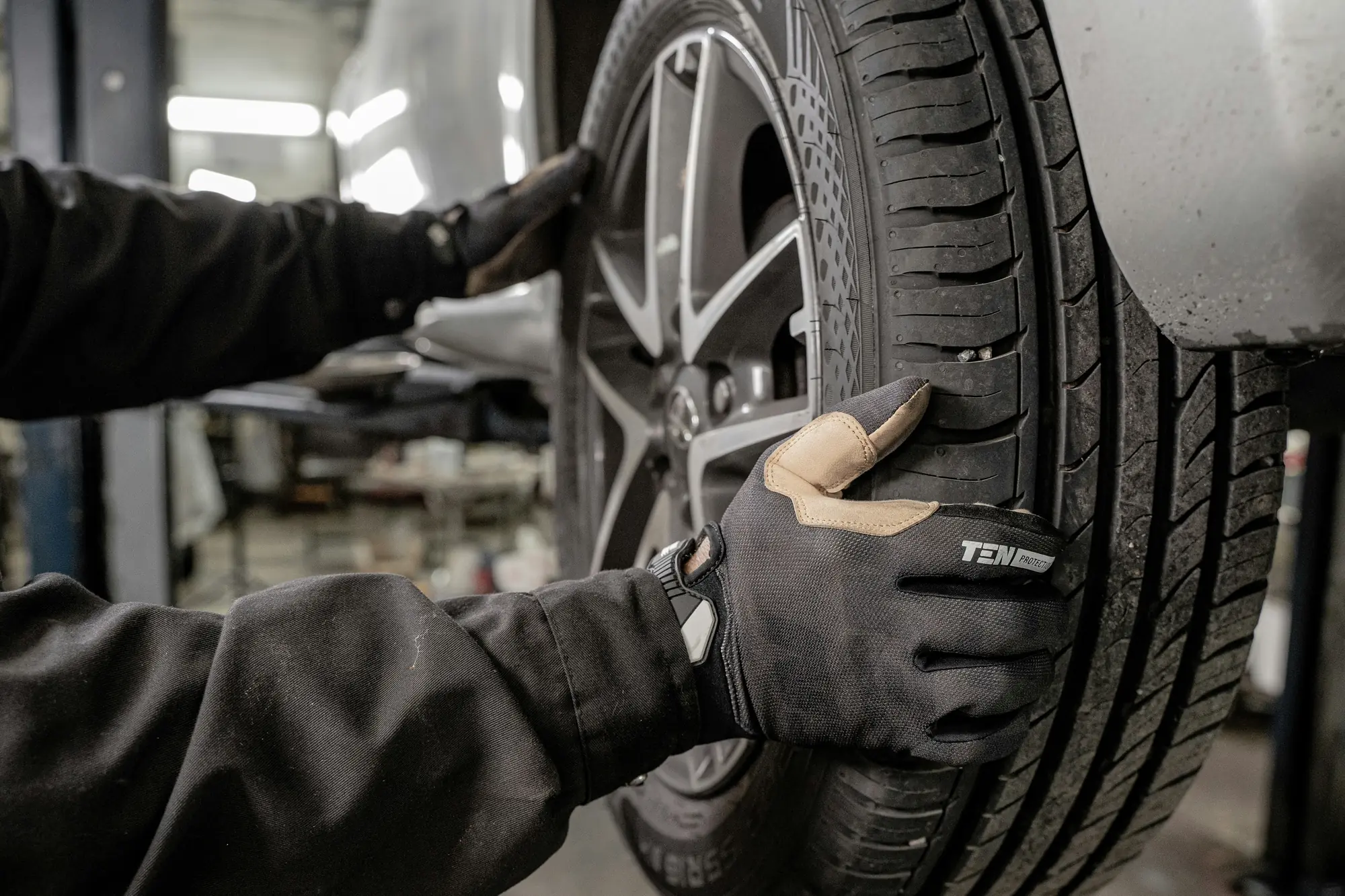 Gloved hands fitting a car tyre